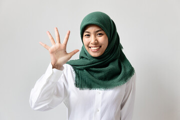 Wall Mural - Young Muslim woman pointing up five fingers for raising 5 points concept