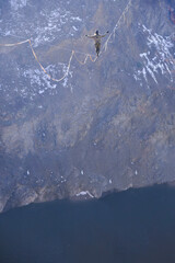 Brave man walking across the lake on a highline