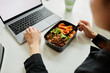 © Seventyfour - Close up of young woman enjoying healthy lunch with vegetables while using laptop, copy space
