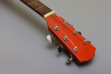 Guitar Headstock With Metal Pegs On A Gray Background