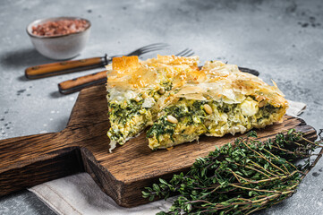 Greek Pie Spanakopita with Spinach and Cheese on wooden board. Gray background. Top view