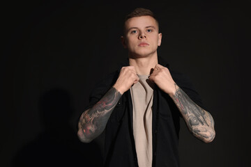 Wall Mural - Young man with tattoos on black background