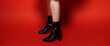 Black stylish boots on a red background. Shoe store banner, space for text