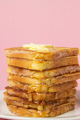 Wall Mural - eggy bread on a pink background. Butter melts on a stack of eggy breads. Tasty breakfast.