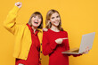 Woman 50s in red shirt have fun with teenager girl 12-13 years old. Grandmother granddaughter hold use work on laptop pc computer do winner gesture isolated on plain yellow background. Family concept.