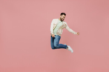 Wall Mural - Full body young expressive singer happy caucasian man 20s in trendy jacket shirt jump high play guitar gesture isolated on plain pastel light pink background studio portrait. People lifestyle concept.