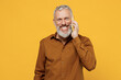 © ViDi Studio - Smiling friendly elderly gray-haired bearded man 40s years old wears brown shirt talk speak on mobile cell phone conducting pleasant conversation isolated on plain yellow background studio portrait.