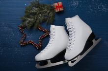 Pair Of Ice Skates With Christmas Decor On Blue Wooden Background, Flat Lay