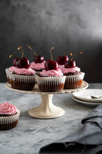 Chocolate Cupcakes With Fresh Cherries And Pink Cream On Cake Stand. Beautiful Dessert. Dark Background.