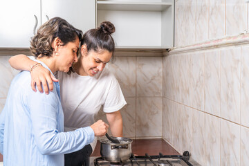 Lesbian couple cooking together while embracing at home