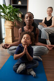 Fototapeta Nowy Jork - Little boy practicing yoga with his mother and meditating in lotus position