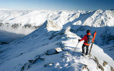 Wall Mural - Climber on top of a mountain in the background of a landscape of snowy mountains. Alps range tourism.  Winter vacations, active lifestyle, skiing and trekking concept.