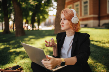 Pretty young caucasian woman go for a walk at park with coffe and laptop. Working outdoors