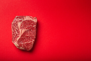 Wall Mural - Raw meat beef prime cut steak Ribeye on clean red background from above, beefsteak concept banner minimalism with space for text