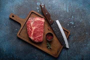 Canvas Print - Raw meat beef marbled prime cut steak Ribeye on rustic concrete kitchen table background from above with big knife and spices, beefsteak concept