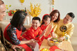 © DragonImages - Happy family enjoying nuts and candied fruits with tea when celebrating Lunar New Year at home
