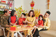 © DragonImages - Three generation family celebrating Tet at home, talking and enjoying tea with candied fruits