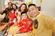 © DragonImages - Cheerful man in traditional ao dai dress photographing with family at Lunar New Year celebration