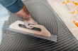 © hedgehog94 - Flooring and tiling. Professional tiler placing floor tiles on adhesive surface.