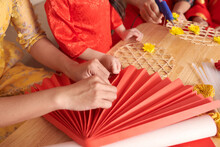 Woman Making Fan Out Of Red Paper To Decorate House For Chinese New Year