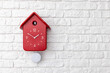 Red cuckoo clock on white brick wall 