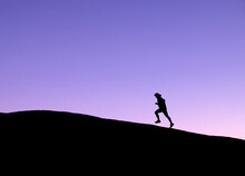 Male Trail Runner Silhouetted Against Purple Evening Sky