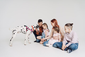 Young Family with kids playing with a dalmatian dog on white background