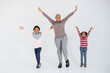 © sofiko14 - Beautiful african american muslim woman with two cute daughters raising hands and smiling on camera while standing in studio. Concept of family, happiness and emotions.