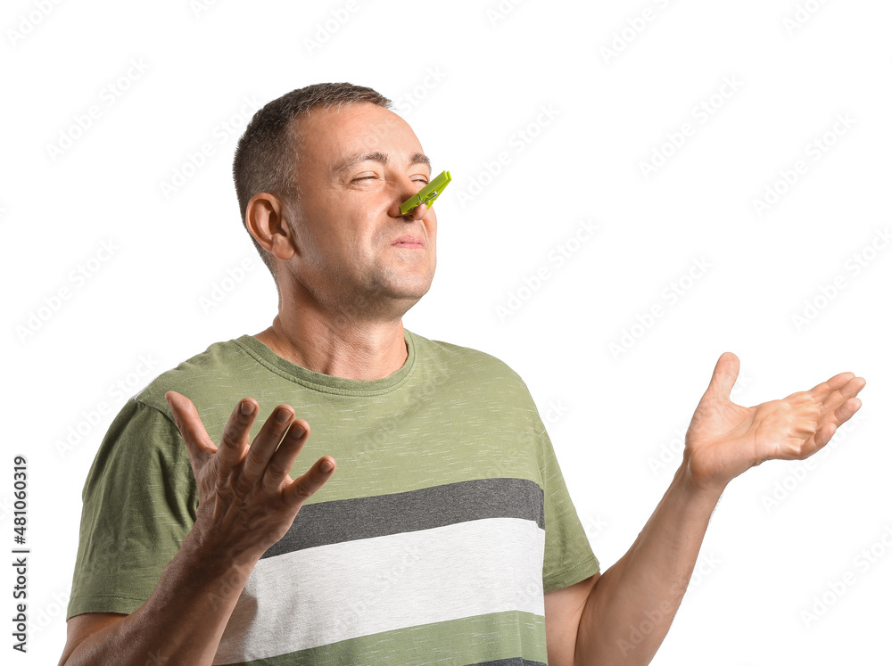 Ill mature man with clothespin on his nose against white background
