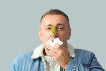 Poster - Ill mature man with clothespin on his nose against grey background