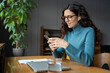 © DimaBerlin - Young businesswoman use smartphone online apps for business social media management and ads. Female distance manager worker checking email messages on mobile phone sitting at desk with closed laptop