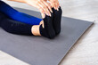 Close up Top view to hands holding foot of a female sitting on a yoga mat outdoors on a wooden floor