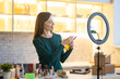© zinkevych - Smiling young woman presenting hairspray during online beauty tutorial