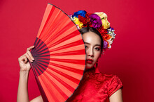 Beautiful Asian Woman Wearing Traditional Dress With Flower Chaplet Holding Red Fan In Isolated Studio Background For Chinese New Year Concept