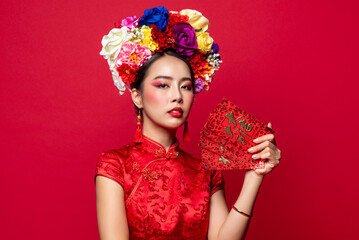 Wall Mural - Elegant Asian woman in traditional oriental costume holding red envelopes or Ang Pow in isolated background for Chinese new year concepts, foreign text translates as great luck great profit