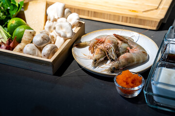 Cooking ingredient, lime, mushroom, shallot, lemon grass, onion, chilli, tobiko, bergamot, shrimp and cheese in wood box plate. They are ready for meal cooking.