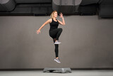 Fototapeta Sypialnia - 
Stepp jump, step fitness.
Sports training, a young attractive woman is exercising in a class at a fitness club