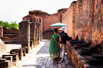 Travelers thai people lover couple people wearing traditional antique thai clothes travel visit respect praying in ancient ruins of Wat Prasat Nakhon Luang Temple in Phra Nakhon Si Ayutthaya, Thailand