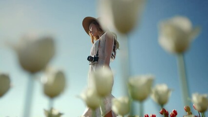 unknown elegant lady with photocamera enjoying summer day in park with flowers.