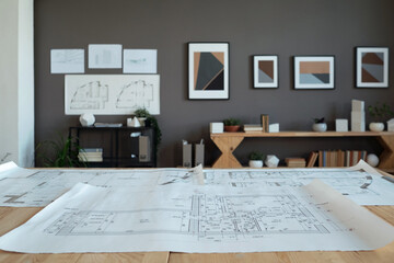 Poster - Interior of contemporary office of engineers or architects with large unrolled blueprint with sketch on their workplace
