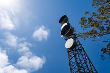 Wall Mural - Looking up at telecommunications tower against blue sky with copy space