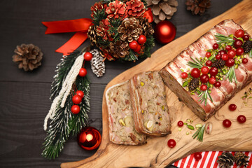 Traditional French terrine covered with bacon on dark wooden background with Christmas decorations