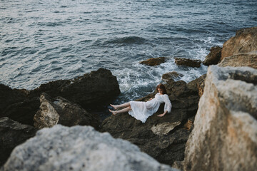 Poster - woman lying on rocky coast with cracks on rocky surface view from above