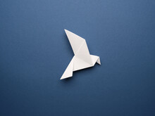 White Origami Pigeon On A Blue Paper Background, Peace Or Freedom Concept