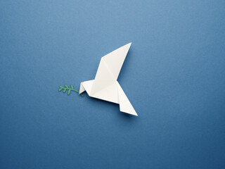 Wall Mural - White origami pigeon on a blue paper background, peace or freedom concept