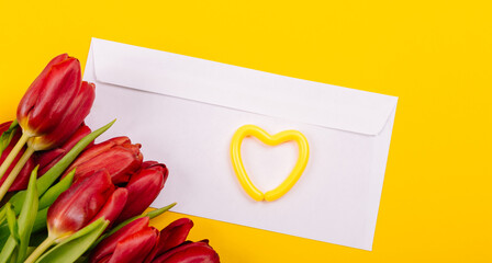 Banner with white gift certificate envelope with heart and bouquet of red tulips on yellow background with copy space, text place. Sample business or invitation card. Happy Valentine Day, Mother Day