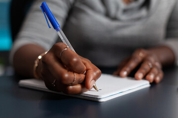 Poster - Close up of hand holding pen to write on textbook file, working from home on business project. Person using notebook to take notes and writing information on paper. Remote work at desk