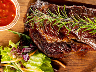 Wall Mural - Beef steak grill with herbs rosemary, garlic and sauce on black background. Top view overlay, close up