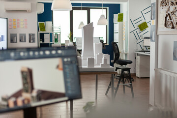 Poster - Table with scale foam model of skyscraper in empty architectural office used for urban development and architecture design. Workstation with 3D render blueprints of real estate buildings.