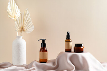 Wall Mural - dark brown cosmetics amber glass bottles on podiums and vase of dried flowers on beige background. s